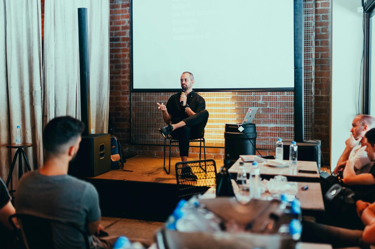 A business seminar with a speaker addressing an attentive audience in a modern conference setting.